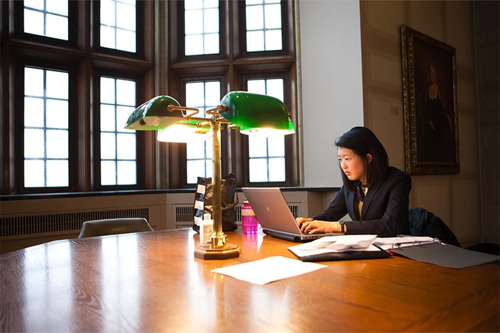 Mayo Clinic Alix School of Medicine student studies next to a green lamp in the library at the Mitchel Student Center on Mayo Clinic's campus in Rochester, Minnesota.