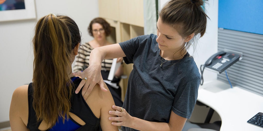 Students practicing patient exams on shoulders