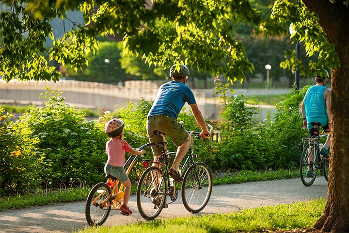 Man and child riding a tandem bicycle on a Rochester bike trail