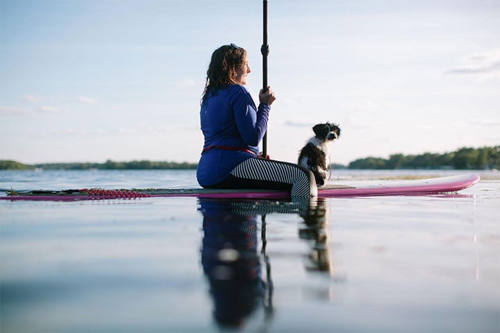 Woman with her dog sitting on a paddleboard in a lake