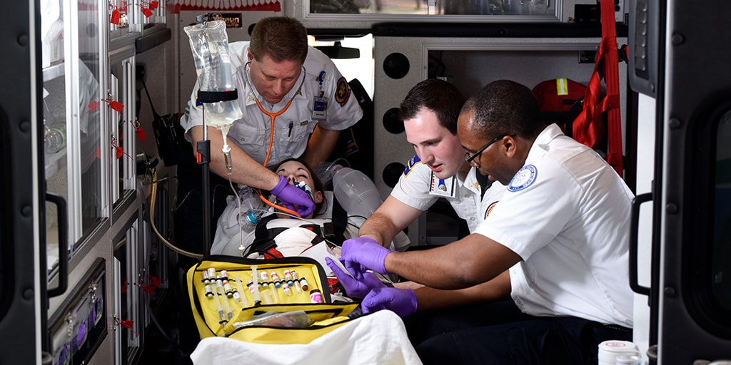 Three paramedics providing emergency care in the back of an ambulance as part of simulated educational opportunity at Mayo Clinic College of Medicine and Science